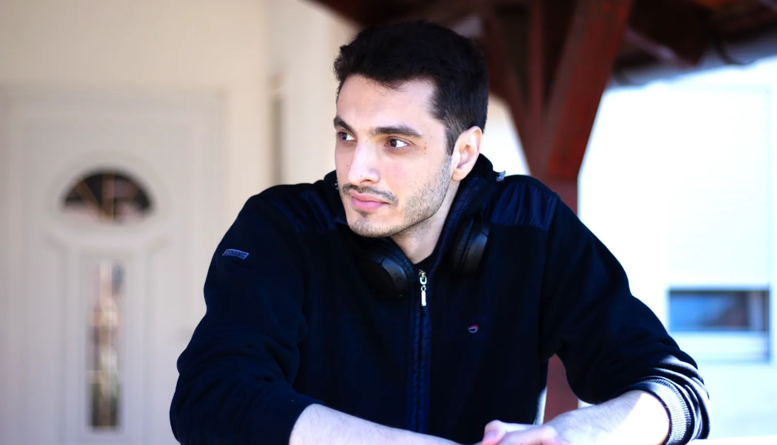 Milos Brakus, leaning on a railing with headphones around his neck.